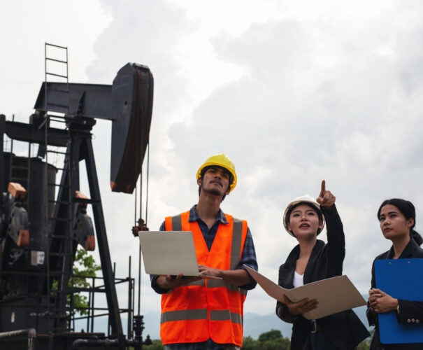 engineering-team-stands-beside-working-oil-pumps-with-sky
